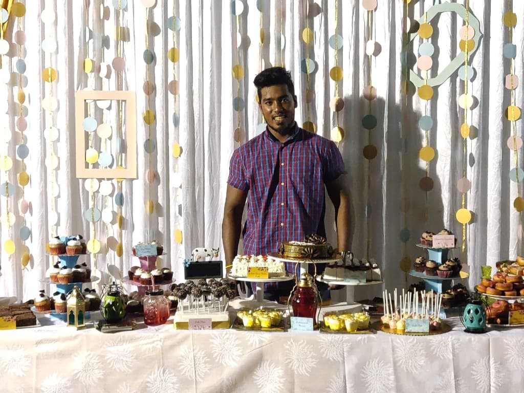 Chef Alex with a spread of cakes, cupcakes and bakes